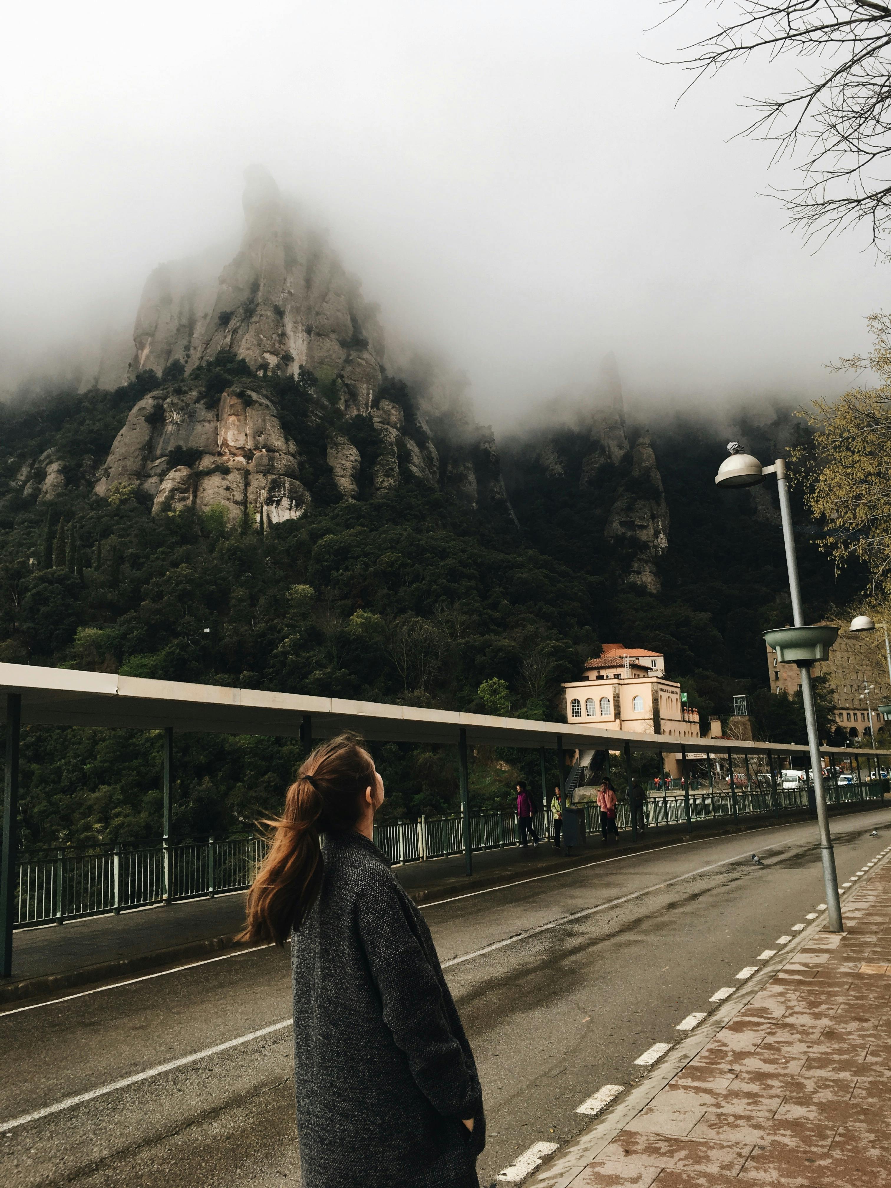 Woman gazing at misty mountains in Monistrol de Montserrat, Spain.